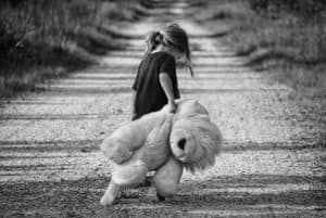 A girls with her teddy bear toy on a dirt road - toy safety for kids